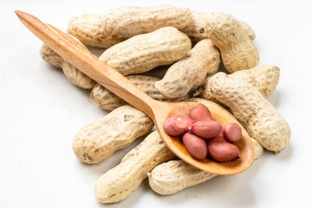 cores in wood spoon and pile of peanuts on gray ceramic plate