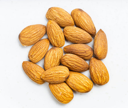 top view of pile of raw almond seeds close up on gray ceramic plateの写真素材