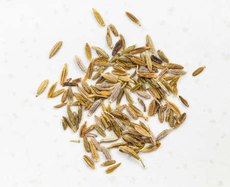 pinch of cumin (cuminum cyminum) seeds close up on gray ceramic plateの写真素材