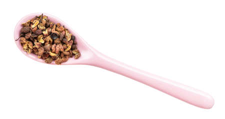 top view of dried pink sichuan pepper in ceramic spoon isolated on white backgrounsの写真素材
