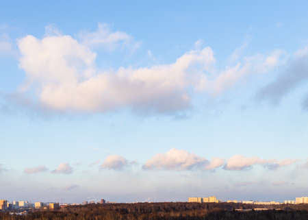 fluffy clouds in blue sunset sky over city park in spring eveningの写真素材
