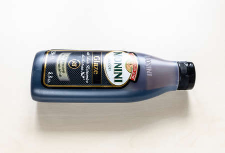 MOSCOW, RUSSIA - JUNE 10, 2021: lying bottle of Monini Glaze with Aceto Balsamico di Modena IGP on pale board. Glazes are the result of simmering the Balsamic Vinegar with flour, sugar and glucoseのeditorial素材