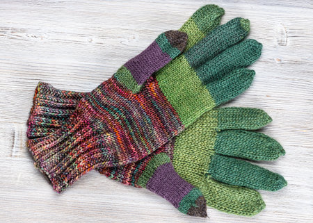 top view of pair of hand knitted woolen gloves on gray wooden table