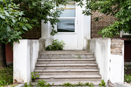 shabby stone porch and closed door of city house on summer evening