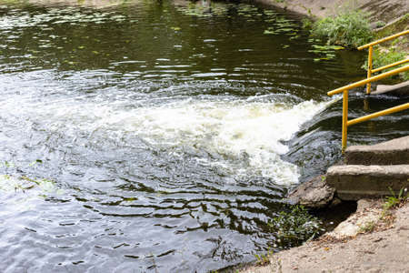 discharge of water from underground river into city pondの写真素材