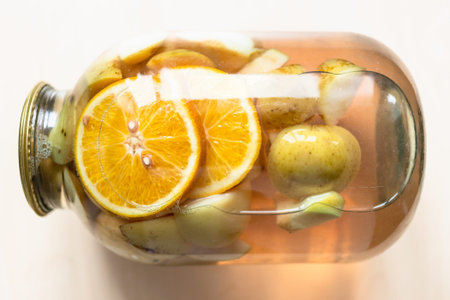 above view of lying 3 liter glass jar of homemade kompot made from sliced fresh apples and oranges...