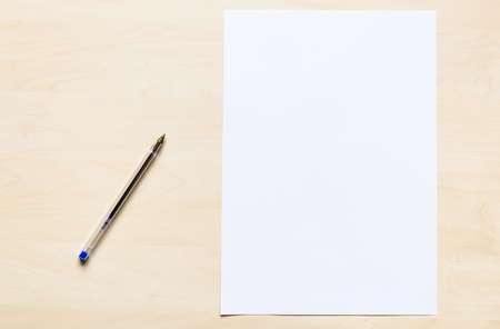 top view of plastic pen and blank sheet of white office paper on light brown wooden boardの写真素材