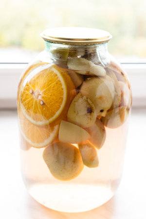 3 liter glass jar with homemade kompot (stewed fruit) made from sliced fresh apples and oranges on...