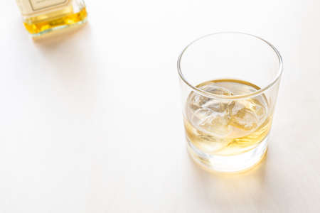 whiskey on the rocks in glass and bottle on background on pale table with copyspaceの写真素材