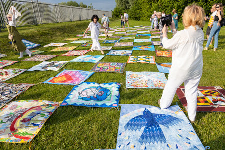Kolomna, Russia - June 11, 2022: participants between their handmade patchwork blankets on green meadow during International Patchwork Festival Soul of Russia in Old Kolomna city on summer dayのeditorial素材
