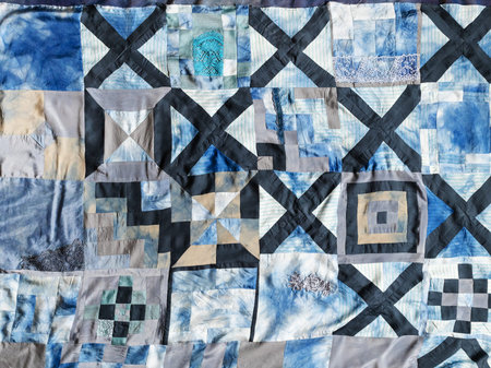 surface of hand-sewn patchwork quilt from pieces of various silk fabrics sewn in convergence...