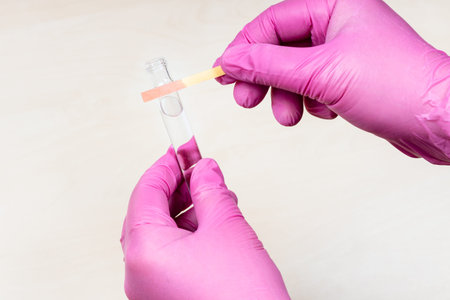 hands holding pink acid litmus test and test tube over light table