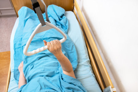 hand of sick woman holds handle of homecare hospital bed at homeの写真素材