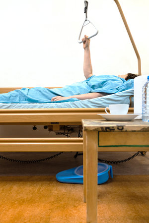 side view of homecare electric hospital bed with sick person holding handle at homeの写真素材
