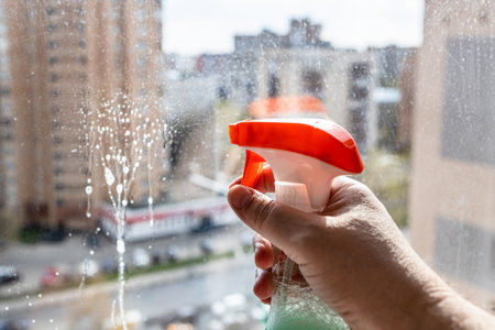 flow splash of washing liquid on glass close up during cleaning home window in high-rise city house on spring dayの写真素材