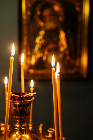 funeral candles burn on altar in front of icon in dark churchの写真素材