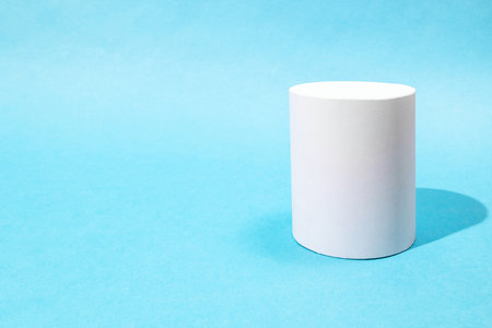 hand-crafted paper cylinder on turquoise blue background with copyspaceの写真素材