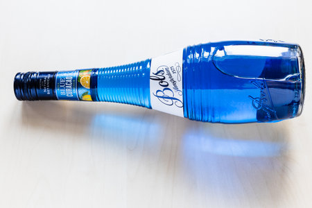 Moscow, Russia - August 2, 2022: lying closed bottle of blue Curacao liqueur made by Bols distillery founded in 1575 in Amsterdam on pale tableのeditorial素材