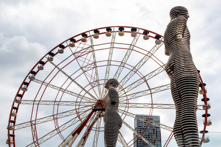Batumi, Georgia - September 16, 2023: Statue of Man and Woman (Ali and Nino) and Ferris wheel on background in Batumi city on autumn day. Statue was made by Georgian artist Tamara Kvesitadzeのeditorial素材