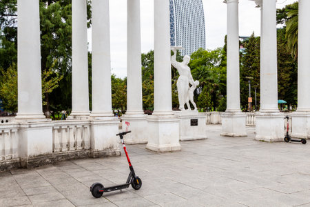Batumi, Georgia - September 16, 2023: electric scooter next to colonnade with monument to Georgian pilot Fadiko Gogitidze at entrance to park on May 6 in Batumi city on autumn dayのeditorial素材