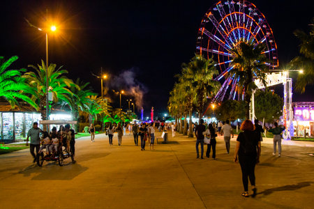 Batumi, Georgia - September 16, 2023: people walk on the promenade near Batumi Festival in Miracle Park in autumn night in Batumi city.のeditorial素材