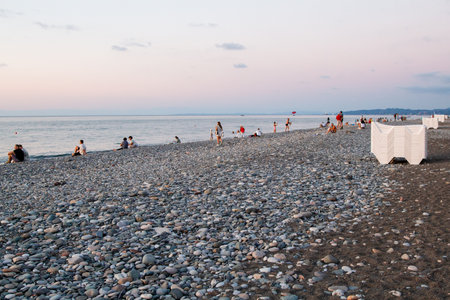 Batumi, Georgia - September 19, 2023: people watch sunset over Black sea on pebble beach in Batumi city on autumn eveningのeditorial素材