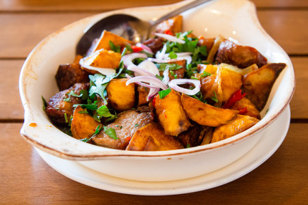 travel to Georgia - portion of Ojakhuri (Georgian dish, fried meat with potatoes) in bowl on wooden...