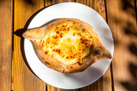 travel to Georgia - top view of Adjarian khachapuri illuminated by sun in local outdoor cafe in Batumi cityの写真素材