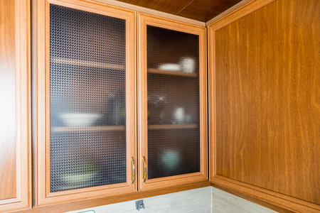 wooden frame wall cabinet doors with ribbed glass in home kitchenの写真素材