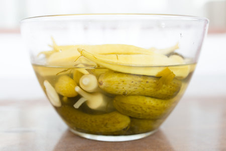 side view of Armenian pickles, cucumber and okra in glass bowl on brown table close up in Yerevan cityの写真素材