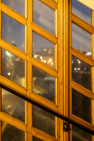 window made of wooden planks and glass inserts illuminated by electric light in evening