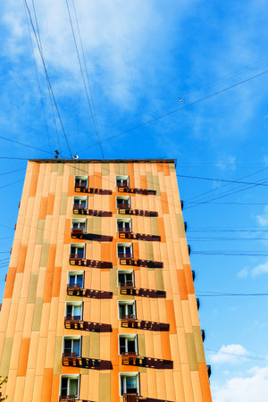 orange multi-story urban house and electric wires and cables in blue skyの写真素材