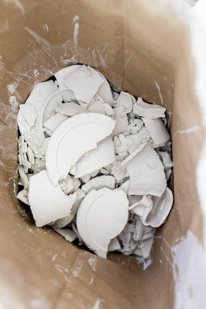 top view of shards and fragments of unfired porcelain in cardboard box