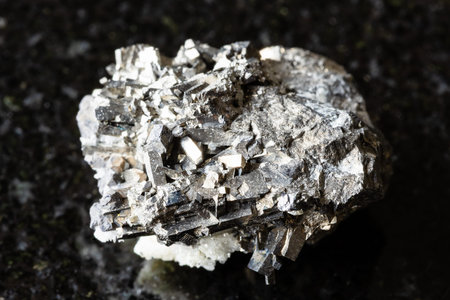 sample of raw arsenopyrite mineral on black granite background close up from Primorye, Russia