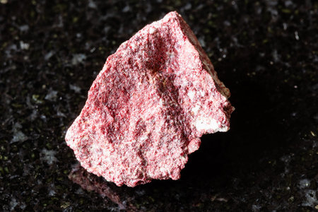 sample of raw cinnabar mineral on black granite background close up from Kyrgyzstan