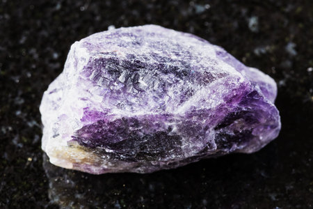 sample of rough amethyst rock on black granite background close up from Russia