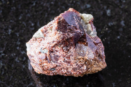 sample of raw eudialyte mineral on black granite background close upの写真素材