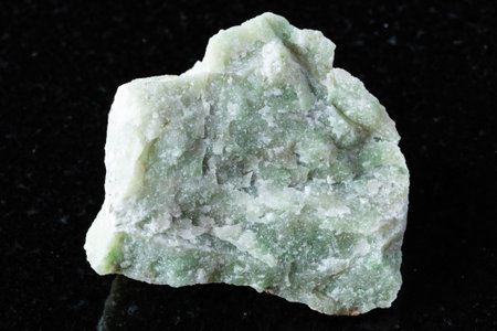 sample of raw rodingite mineral on black granite background close up from Kazakhstan