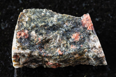 sample of raw gneissoid granite mineral on black granite background close up from Karelia, Russia