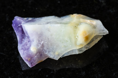 sample of raw opal mineral on black granite background close up from Mexico