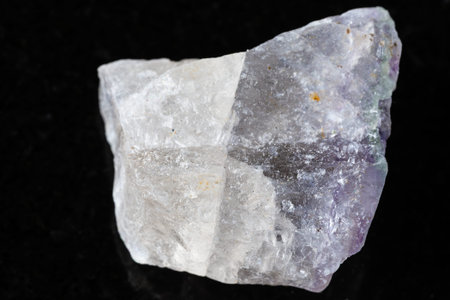 sample of unpolished fluorite mineral on black granite background close up
