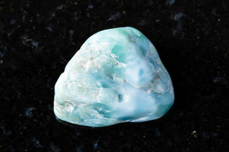 sample of raw larimar mineral on black granite background close up from Dominicana
