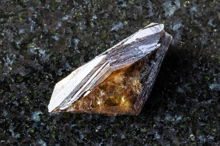 sample of raw twinned brown titanite crystal on black granite background close up from Subpolar Urals, Russiaの写真素材