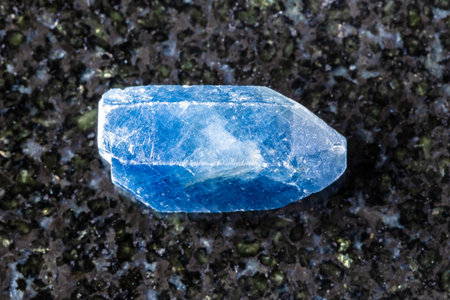 sample of raw single blue sapphire crystal on black granite background close up from Tanzaniaの写真素材