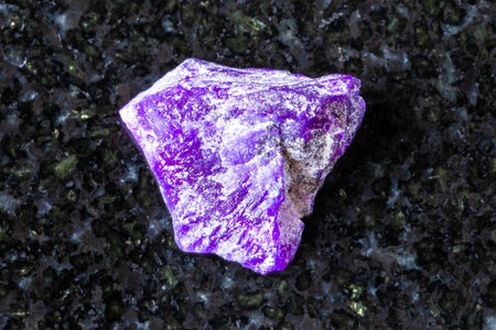 sample of raw sugilite mineral on black granite background close up from South Africaの写真素材