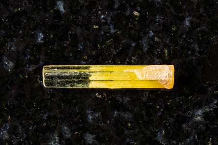 sample of raw heliodor yellow beryl crystal on black granite background close up from Transbaikalia, Sherlovaya Gora, Russiaの写真素材
