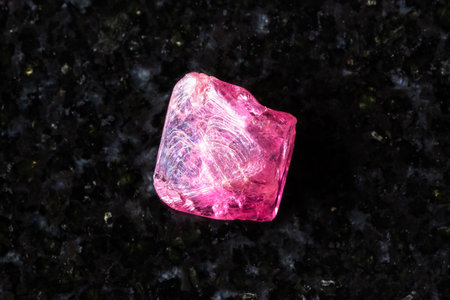sample of raw pink spinel crystal on black granite background close up from Vietnamの写真素材