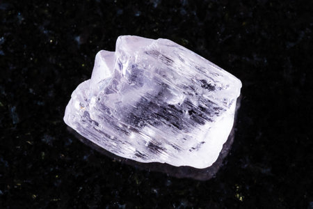 sample of raw kunzite mineral on black granite background close up from Afghanistanの写真素材