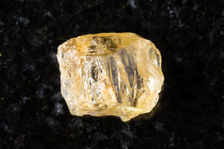sample of raw yellow scapolite crystal on black granite background close up from Tajikistanの写真素材