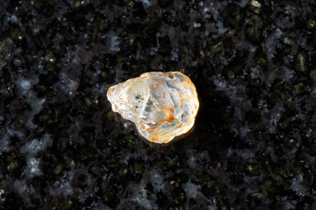 sample of unpolished colorless sapphire mineral on black granite background close up from Madagascarの写真素材